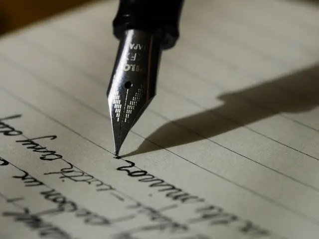Close-up of a fountain pen nib writing in cursive on lined paper